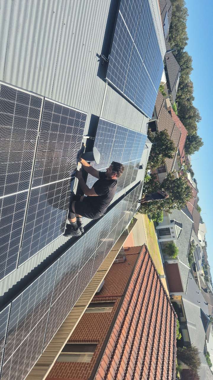 Perth Solar and Air installer working within a completed rooftop solar array