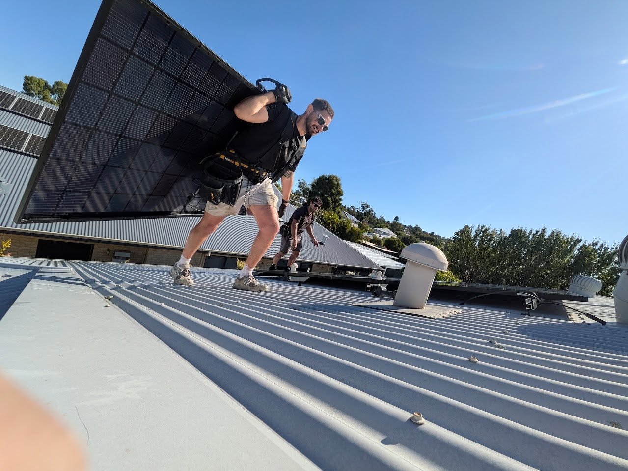 PSA installers positioning a solar panel on a Perth roof